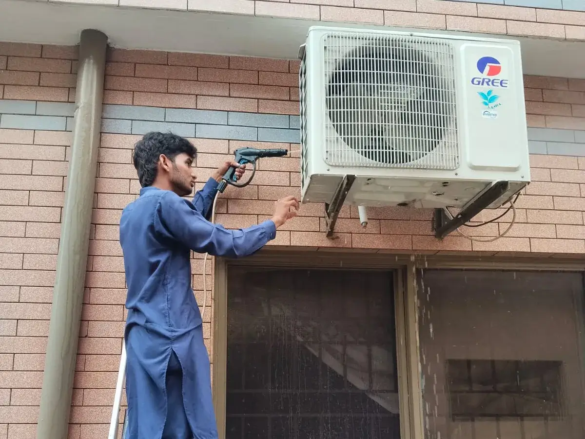 Technician servicing an outdoor AC unit in Rawalpindi